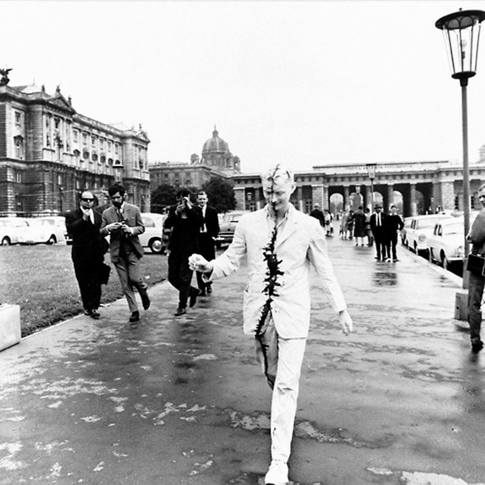 Artist Günter Brus strolling through the centre of Vienna in Austria the day after his first public action, ‘Self-Painting/Self-Mutilation’ in 1965. Painted entirely in white with a black strip over his face and body, Brus was almost immediately arrested by the police for being potentially disturbing to the public (as noted by Tracey Warr and Amelia Jones in The Artist’s Body)