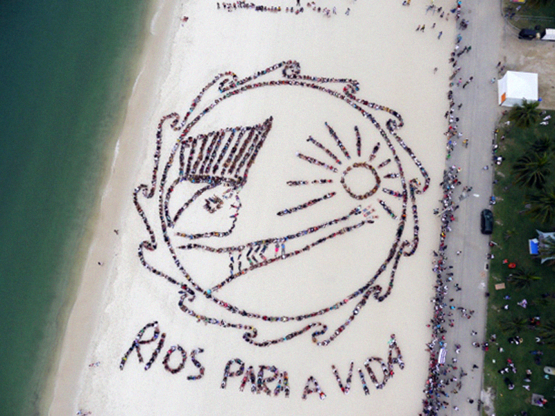 RIVERS FOR LIFE: A living art work using Rio de Janeiro's Flamengo Beach as a canvas. The image was an artistic collaboration between world-renowned aerial artist John Quigley and a visionary committee of indigenous peoples including Aldamir Sataré-Mawé (Amapá), Sheyla Juruna (Pará), Dione Vison Terena (Mato Groso do Sul), Augusto Kaigamg (Rio Grande do Sul), and Capitao Potuguara; June 2012.