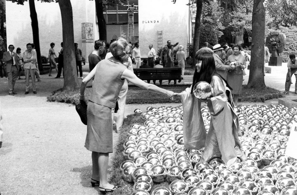 YAYOI KUSAMA with NARCISSUS GARDEN, Venice Biennale, 1966. Kusama offered the 1,500 mirrored balls for sale at 1200 lire ($2 each). She was prohibited from doing this and gave out leaflets praising her own work as she had crashed event wearing a golden kimono. Image courtesy: Ota Fine Arts, Tokyo / © Yayoi Kusama, Yayoi Kusama Studio Inc.