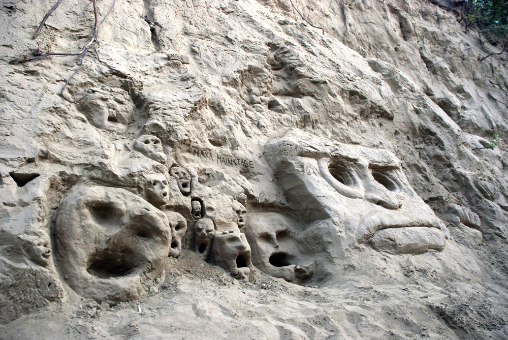 A mysterious growth of faces and masks in the rock.