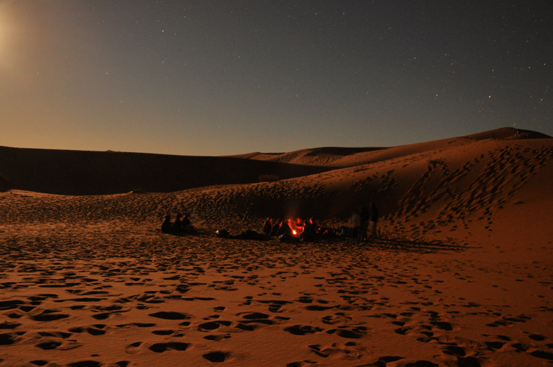 Moonrise at night in the desert, in the left foreground of the camp.