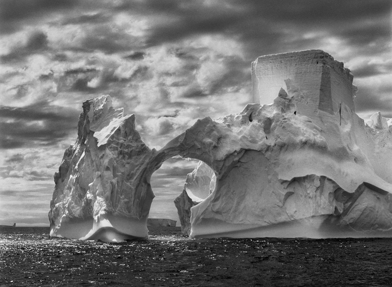 Iceberg between Paulet Island and the South Shetland Islands on the ANTARCTIC Channel. At sea level, earlier flotation levels are clearly visible where the ice has been polished by the ocean’s constant movement. High above, a shape resembling a castle tower has been carved by wind erosion and detached pieces of ice. The Antarctic Peninsula, 2005.