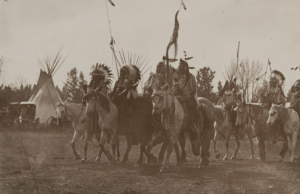 Untitled (Native Americans wearing headdresses on horseback), c. 1910 Photographed by Richard Throssel (Cree, adopted Crow; 1882-1933). Gelatin silver print on paper. Museum of Photographic Arts.